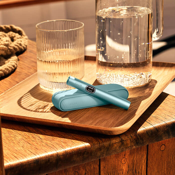Glasses and drinks with IQOS device next to it