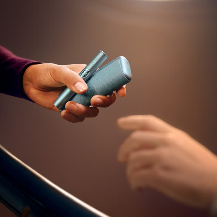 A person giving IQOS to a friend
