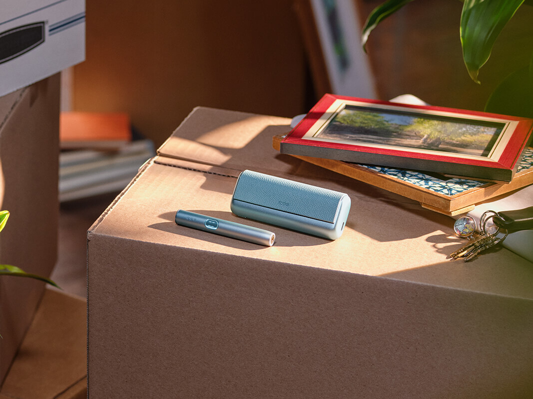 En IQOS ILUMA PRIME-hållare i en persons händer, lamporna är synliga. 