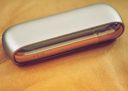 IQOS 3 DUO holder with heatsticks and charger on a dinner table