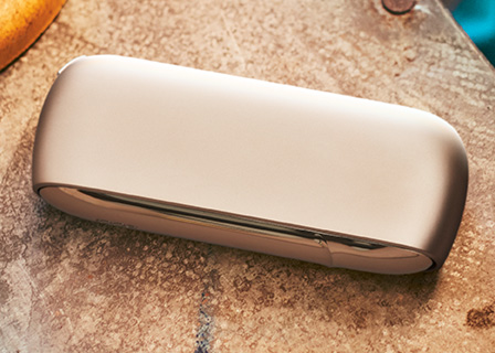 Brilliant gold IQOS 3 DUO holder and charger on an accordion's bellows