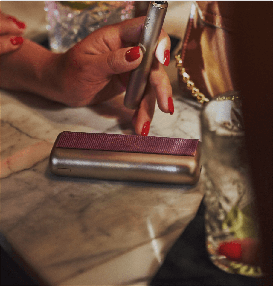 A woman using her IQOS in a bar.