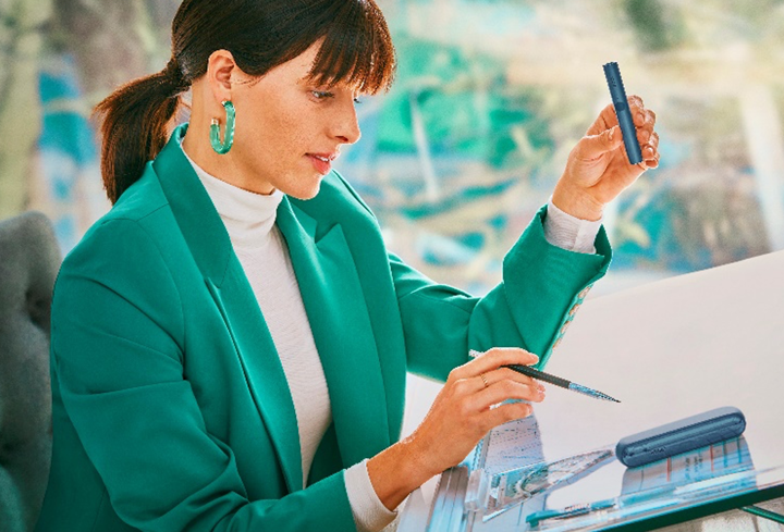 A smiling woman with an IQOS ILUMA device