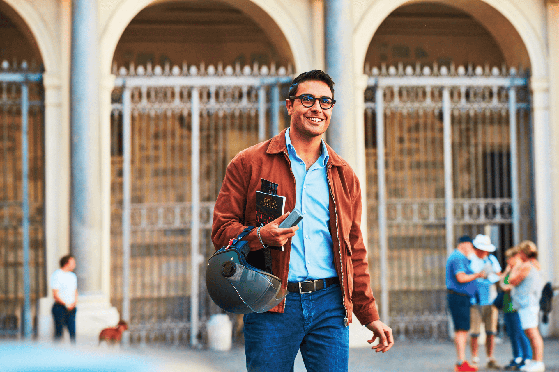 A man holding a book, a helmet and an IQOS device.