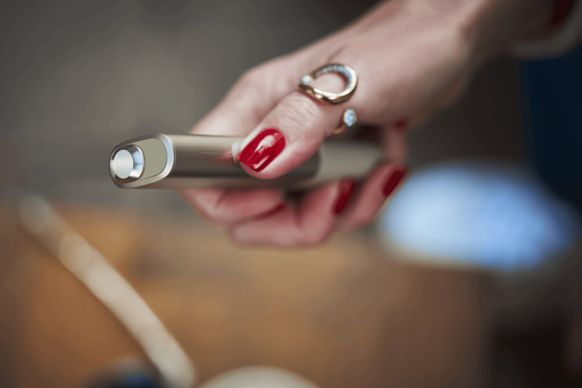 A woman with red nails holding an IQOS device