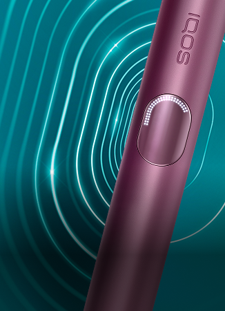 Detalhe de dispositivo IQOS ILUMA i PRIME Vermelho Escuro, orientado para a direita, irradiando um padrão oval concêntrico, sobre fundo turquesa escuro