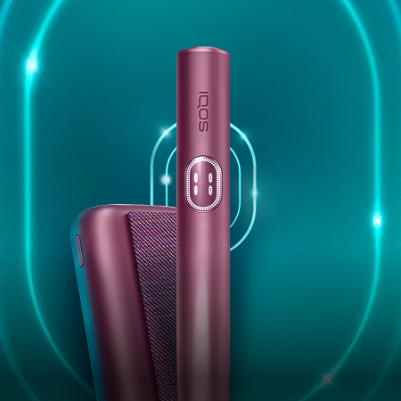 Garnet Red IQOS ILUMA i PRIME-enhet och dess laddare på en mörkturkos bakgrund