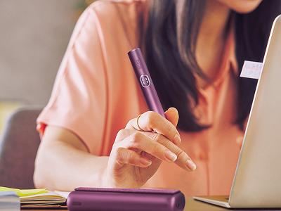 A girl enjoying IQOS while using her laptop