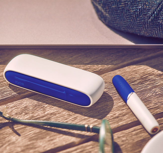 A smiling man holdiing an IQOS device.