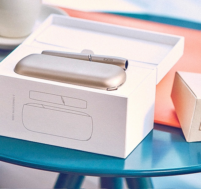 A smiling man holdiing an IQOS device.