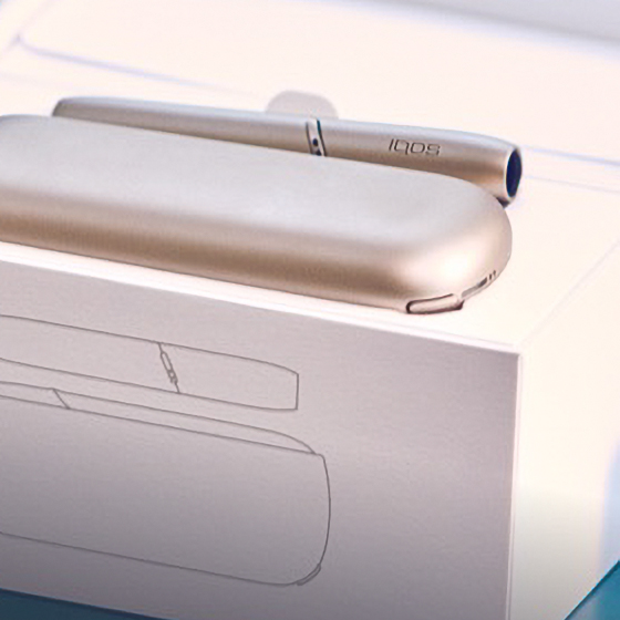 Two women looking at a light blue IQOS device