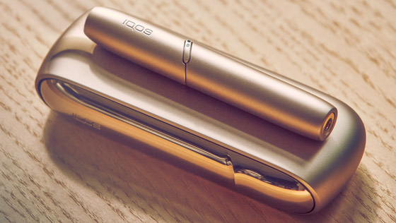 A gold IQOS holder on a closed book.