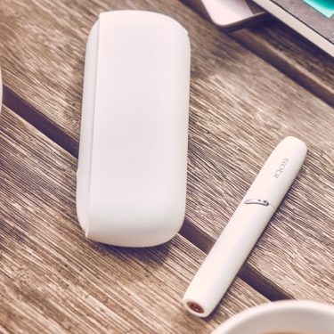 White IQOS 3 DUO holder and charger on a picnic table
