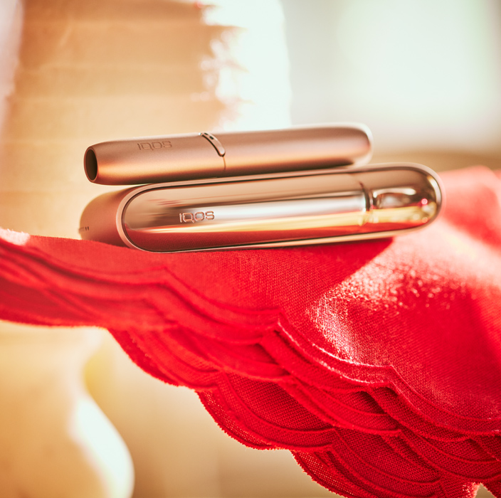 Brilliant gold IQOS 3 DUO holder on charger on red fabric