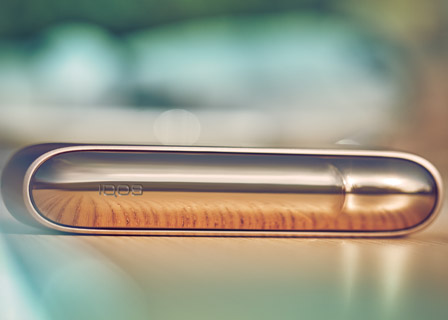 Black IQOS device on a blue book