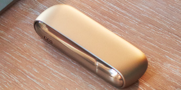 Blond girl with her gold IQOS kit in her hands