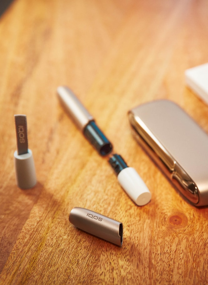 Man with a gold IQOS Duo and a mobile in his hands