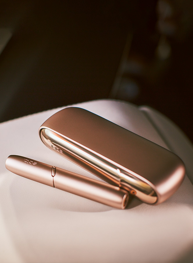 Man with a gold IQOS Duo and a mobile in his hands