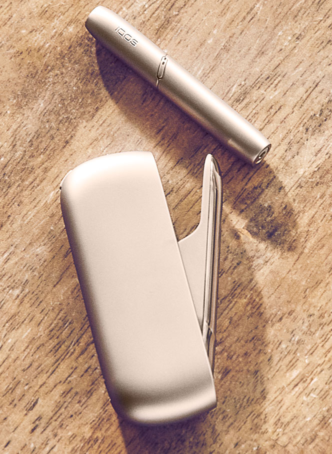 Man with a gold IQOS Duo and a mobile in his hands