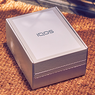 Girl smiling with an IQOS box in her hands