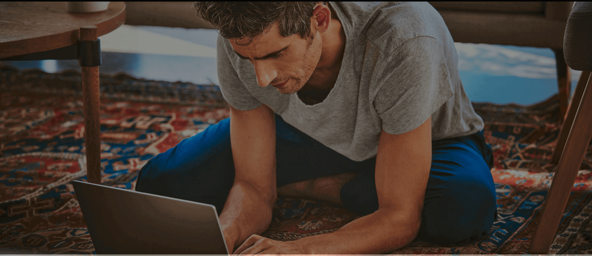 Young man sitting on the floor and looking at his laptop