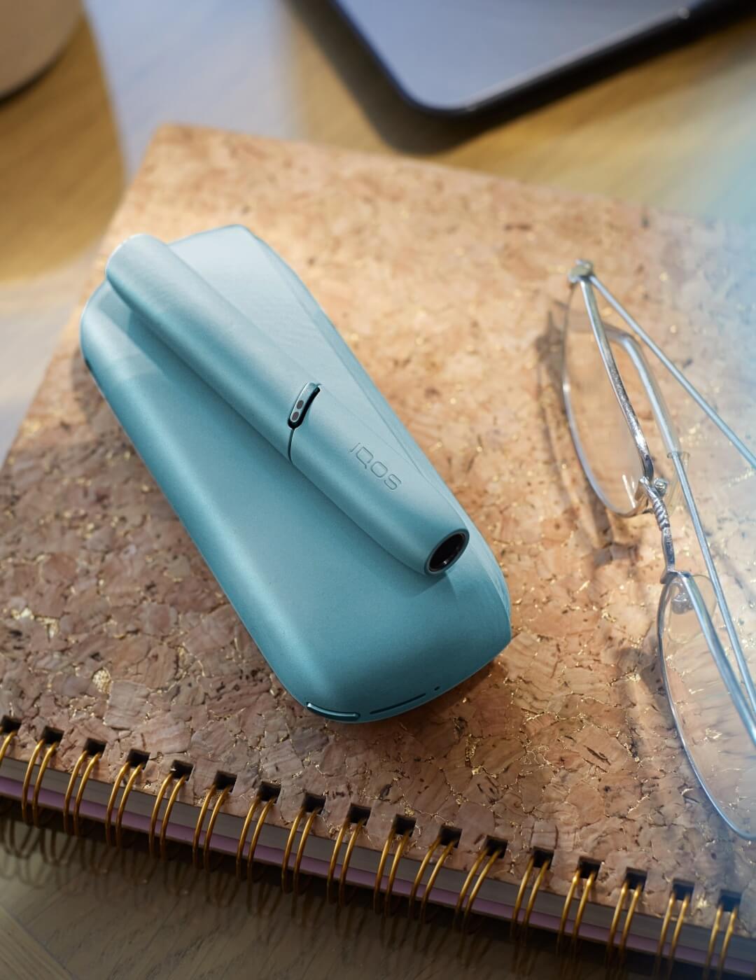 Turquoise device and glasses on a notebook