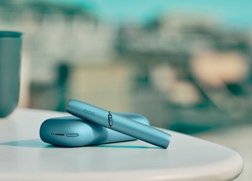 Brilliant gold IQOS 3 DUO holder and charger next to binoculars