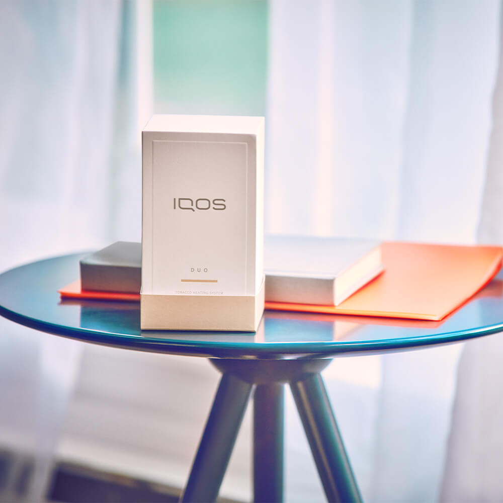 iqos 3 duo box, a box, and a file lying on a small table