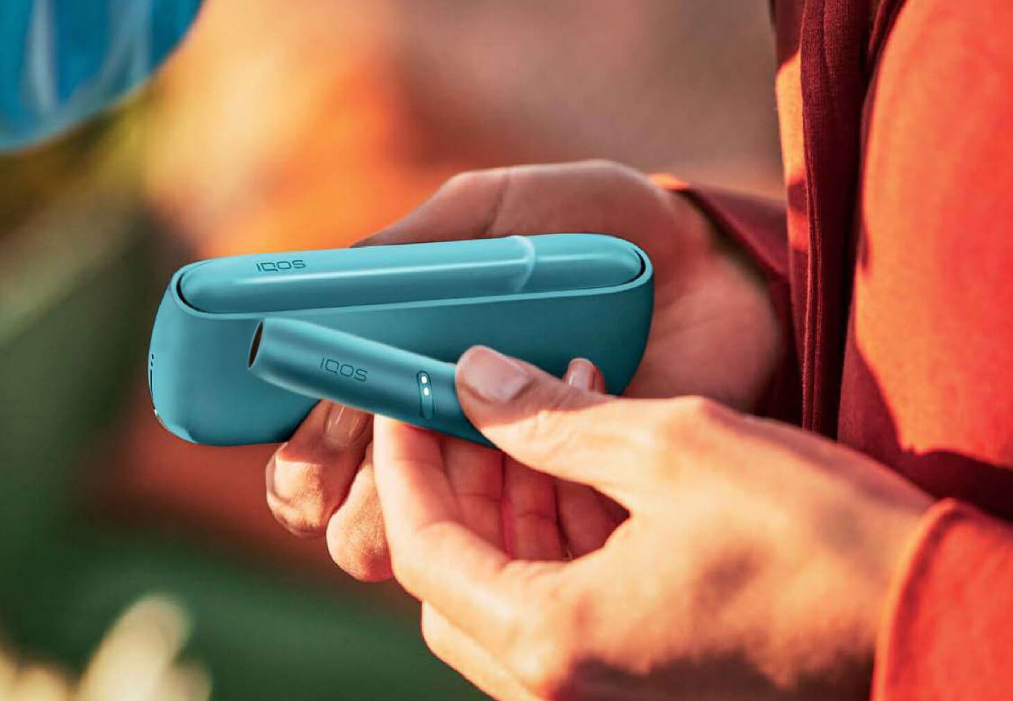 close-up shot of hands holding a blue iqos device