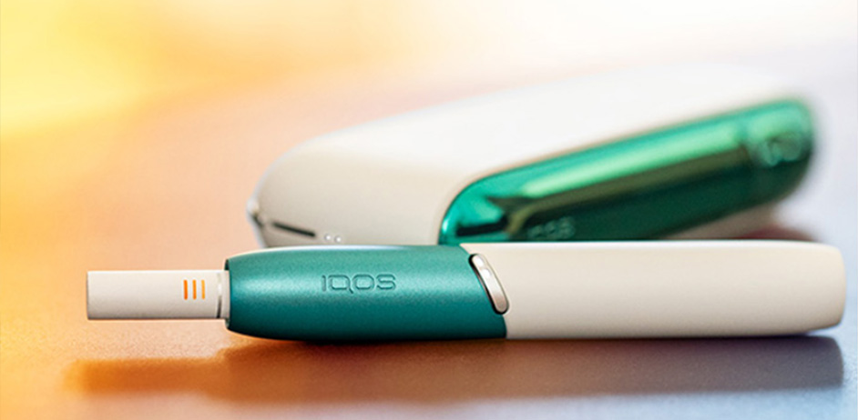 Person am Tisch mit IQOS 3 DUO in der Hand