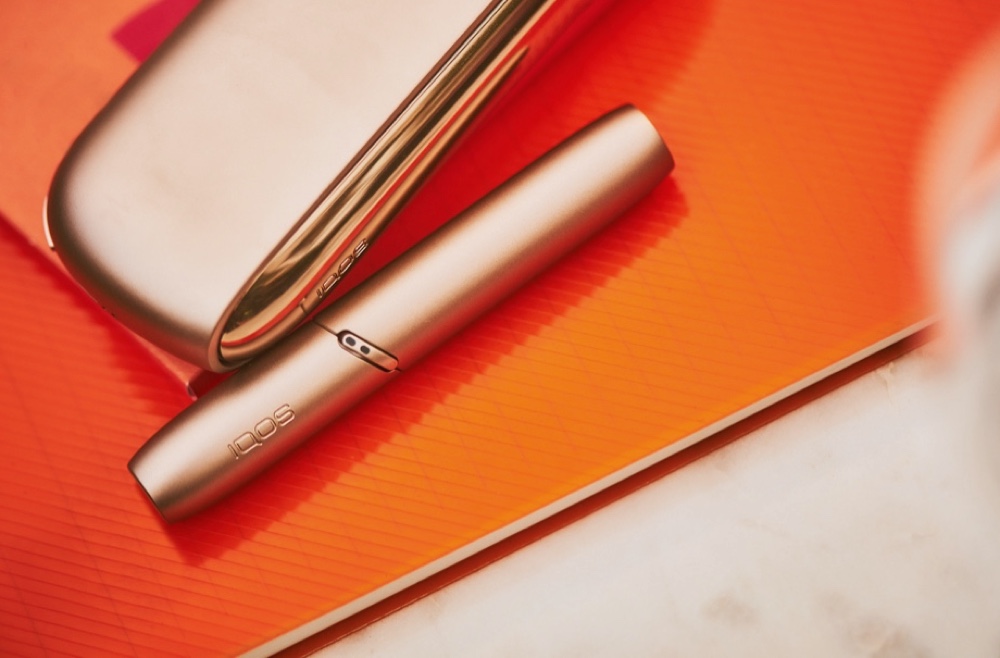 Golden IQOS duo on orange background
